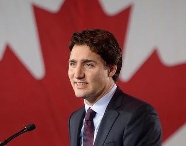 Justin Trudeau w interakcji z ludźmi podczas publicznego wystąpienia, uśmiechnięty i otwarty.