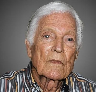 Richard Chamberlain jako ksiądz Ralph de Bricassart z miniserialu „Ptaki ciernistych krzewów”, stojący na tle australijskiego krajobrazu, zamyślony.