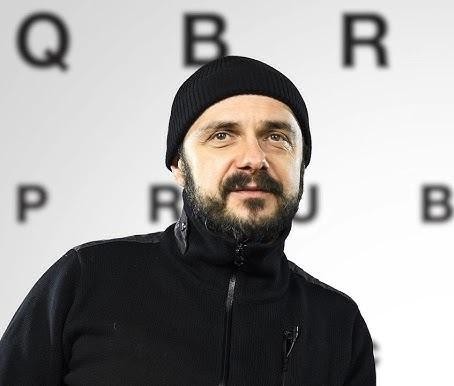 Arkadiusz Jakubik podczas pracy artystycznej, np. na planie filmowym, scenie teatralnej lub podczas koncertu zespołu Dr Misio, ukazujący jego wszechstronność.