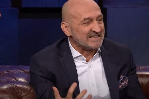 Kazimierz Marcinkiewicz przemawiający na konferencji prasowej, otoczony mikrofonami i kamerami.