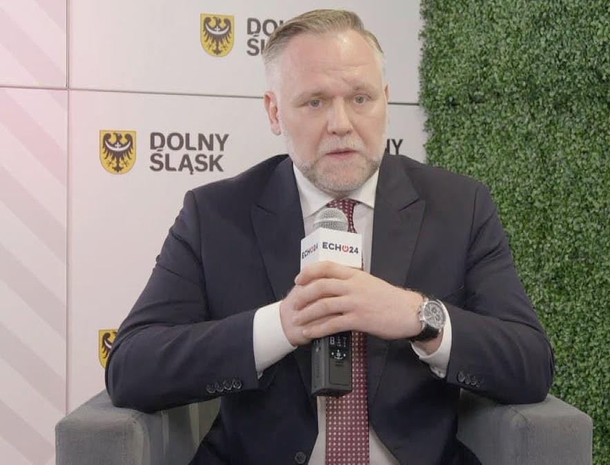 Dawid Jackiewicz podczas wystąpienia publicznego, z mikrofonem, energicznie gestykulujący.