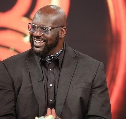 Shaquille O'Neal uśmiechnięty i żartobliwy, pokazujący swoją charyzmatyczną osobowość poza boiskiem.