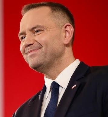 Karol Nawrocki w otoczeniu książek historycznych, symbolizujących jego pasję i pracę.