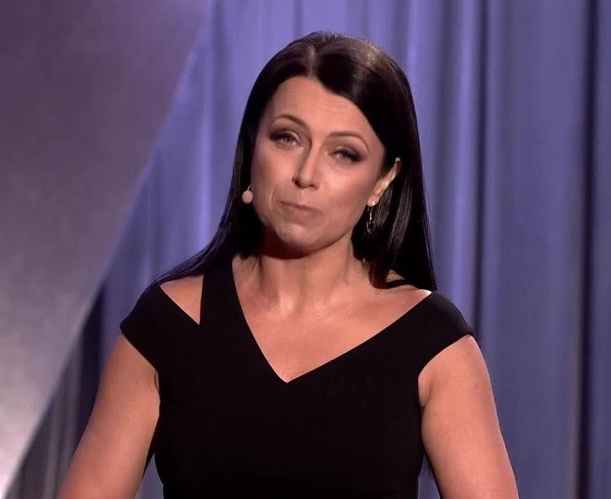 Adrianna Borek na scenie podczas występu kabaretowego, w dynamicznej pozie, z charakterystyczną mimiką i gestykulacją, oddającą energię jej kreacji aktorskiej, z rozmytym tłem publiczności.