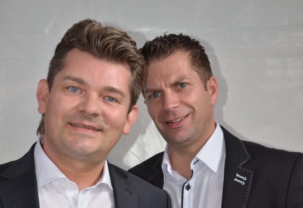 Ryszard Warot, lider zespołu Akcent, śpiewający i grający na klawiszach podczas występu na scenie, otoczony kolorowymi światłami.