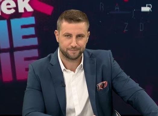 Miłosz Kłeczek podczas prowadzenia programu w studiu telewizyjnym, gestykulujący, co podkreśla jego dynamiczny styl.